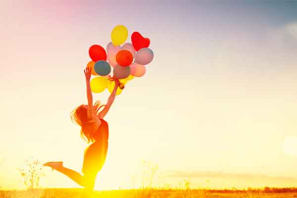 Frau springt mit Luftballons 